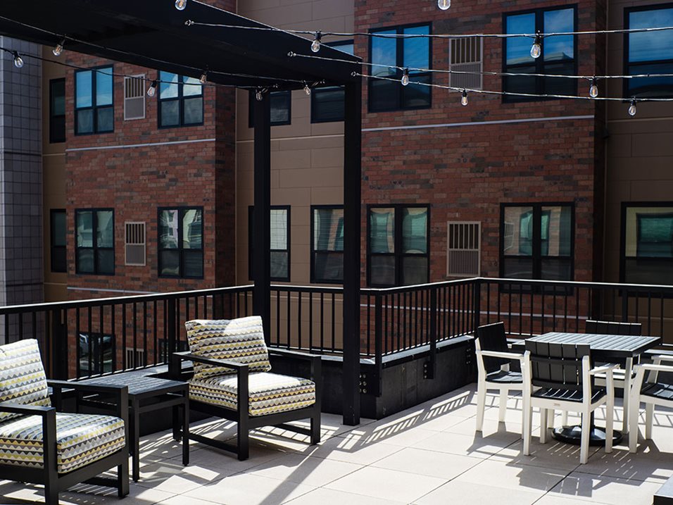 Rooftop patio with modern outdoor seating and string lights in an urban setting.