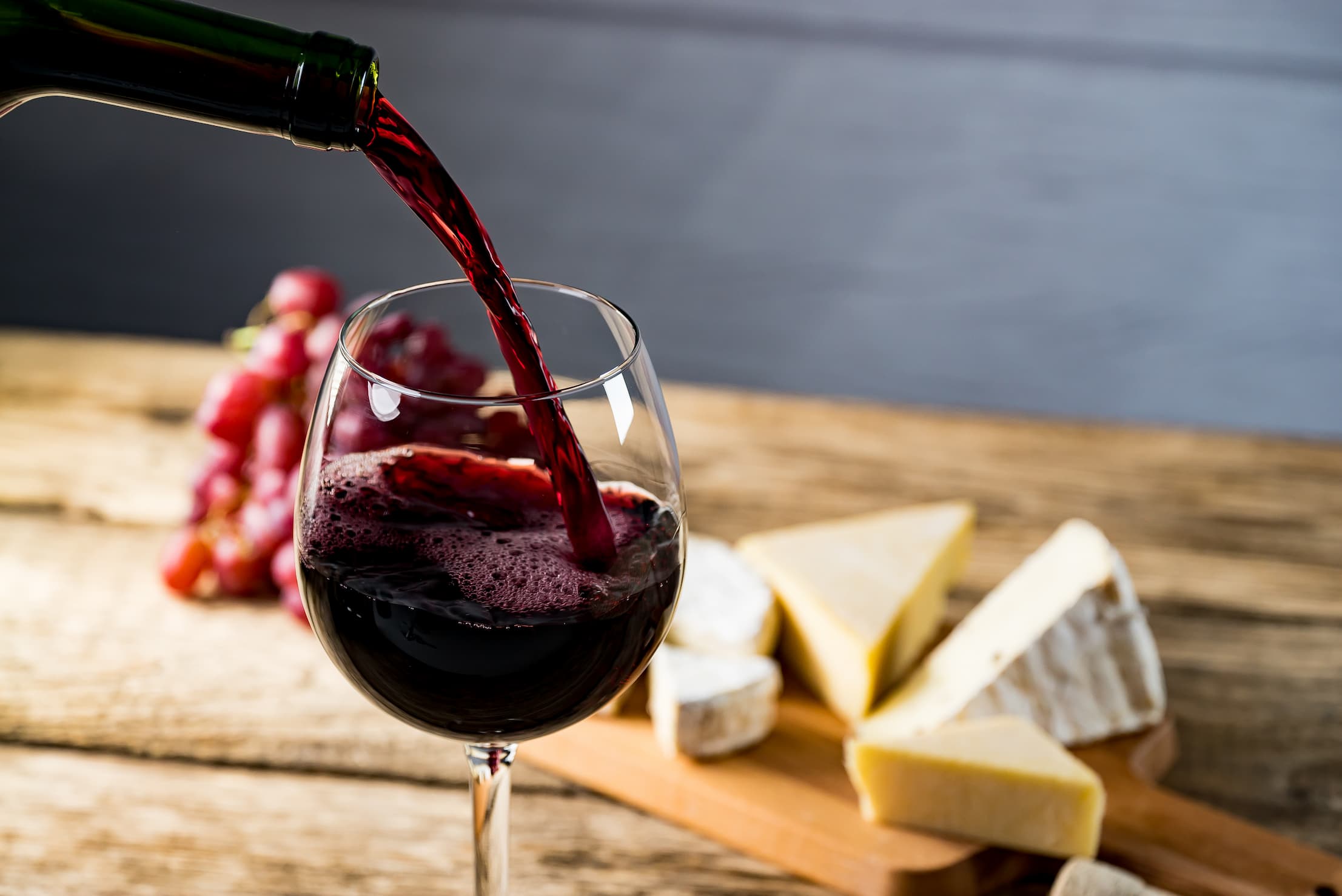 Pouring wine into glass with cheese